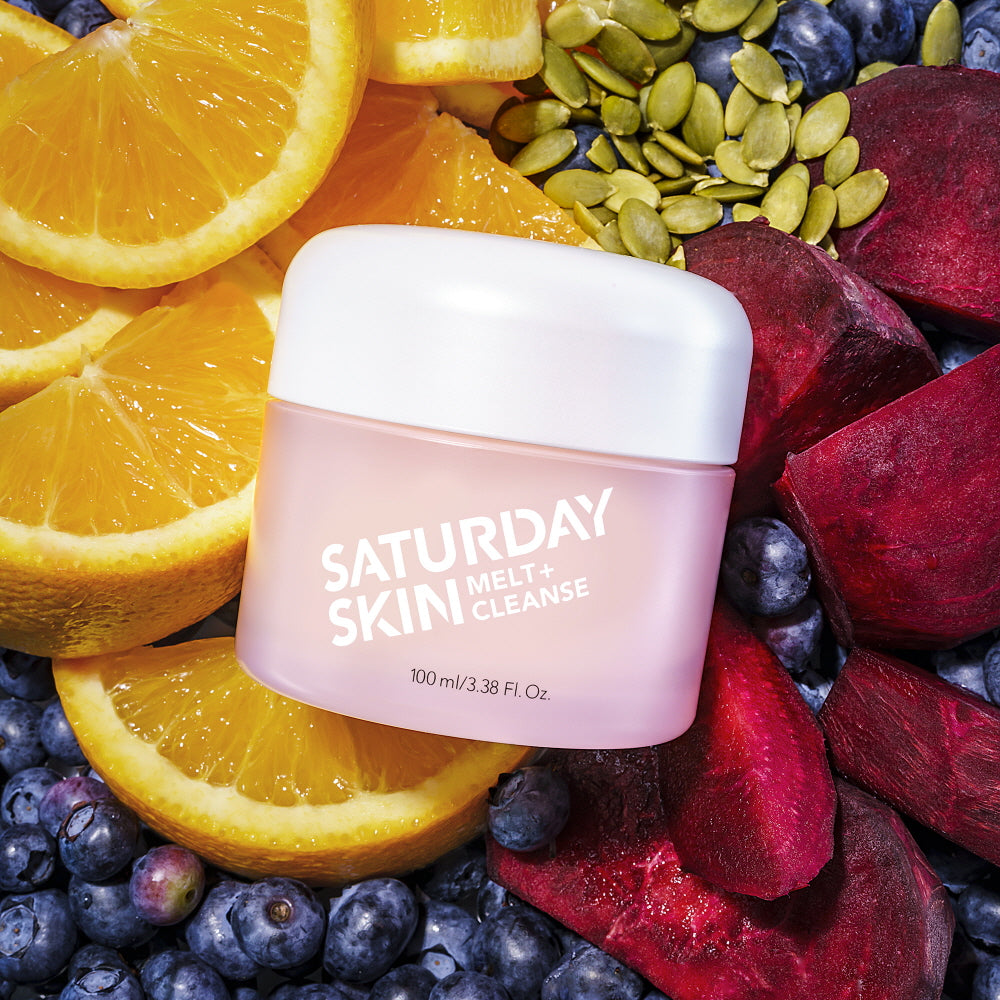 Jar of Saturday Skin skincare product surrounded by fruits and seeds