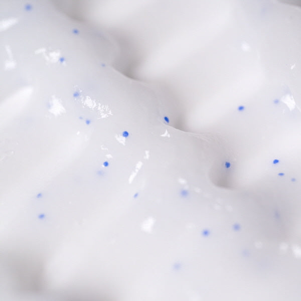 Close-up of white cream with blue specks on a white background