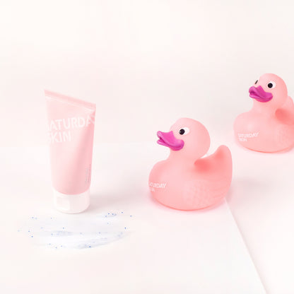 Two pink rubber ducks and a pink tube of cream on a white background