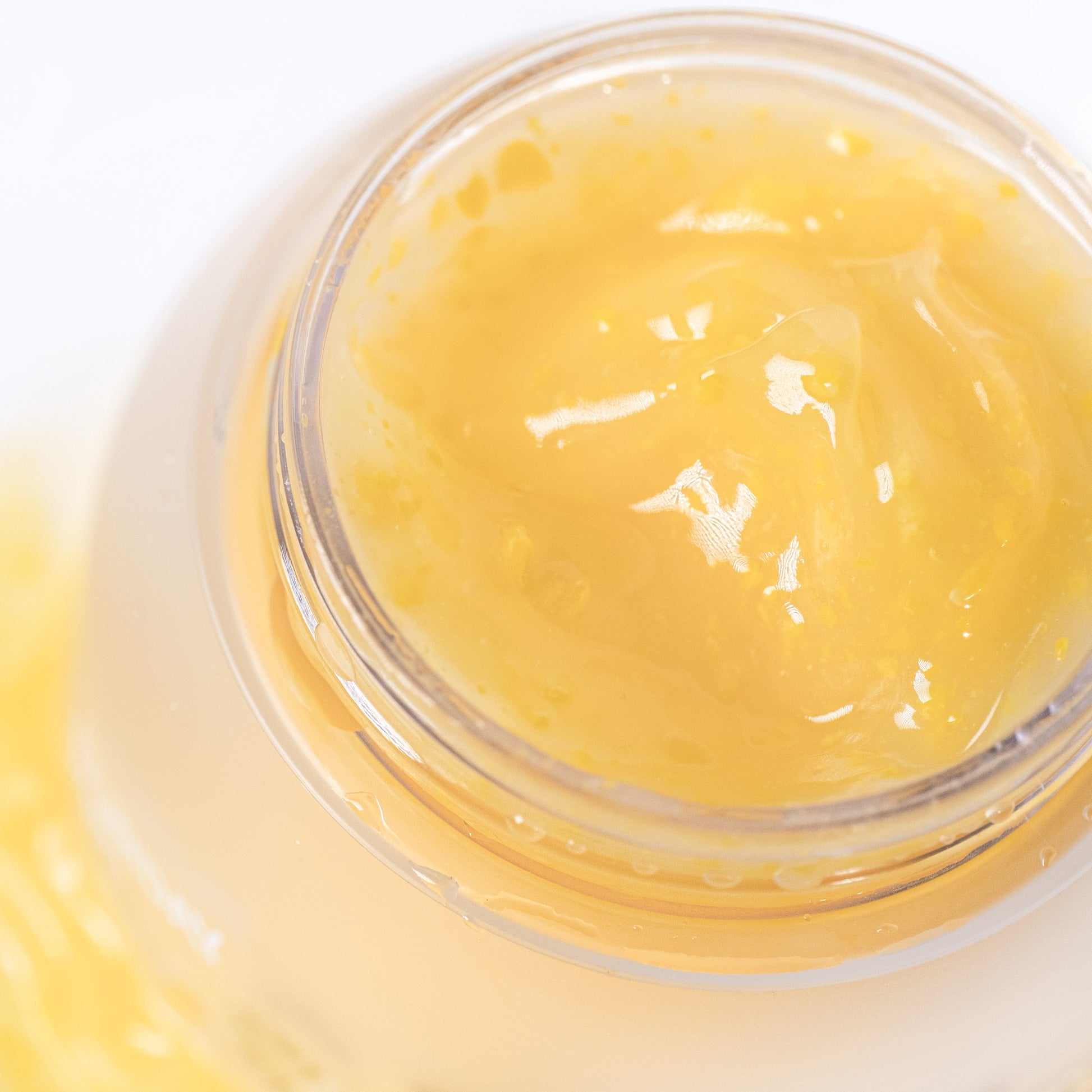 Close-up of a jar of yellow cream with a white background