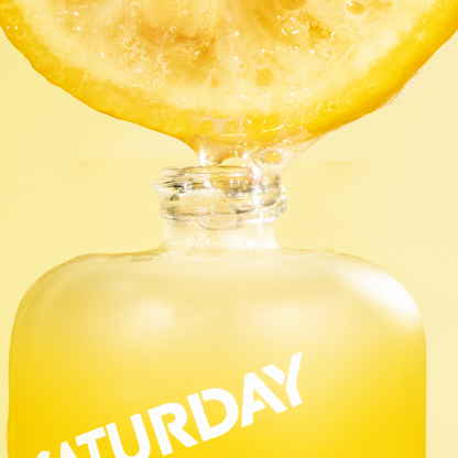 Bottle of 'Saturday' with a lemon slice on a yellow background